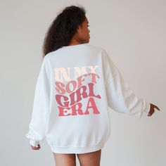 "Our retro In My Soft Girl Era Sweatshirt is designed to capture the essence of the soft girl aesthetic and add a touch of whimsy to your wardrobe. With its adorable smiley design in pink text and the phrase \"In My Soft Girl Era\" elegantly placed on the back, this sweatshirt is perfect for women who want to embrace or continue living their best soft life Ideal for any situation, a unisex heavy blend crewneck sweatshirt is pure comfort. These garments are made from polyester and cotton. This combination helps designs come out looking fresh and beautiful. The collar is ribbed knit, so it retains its shape even after washing. There are no itchy side seams on these sweaters.  - 50% cotton, 50% polyester - Medium-heavy fabric (8.0 oz/yd² (271.25 g/m - Loose fit - Sewn-in label - Runs true to Cute Long Sleeve Sweatshirt With Text Print, Cute Sweater With Letter Print For Loungewear, Cute Letter Print Sweater For Loungewear, Cute Sweatshirt With Text Print And Long Sleeves, Cute Oversized Letter Print Sweater, Oversized Cute Sweater With Letter Print, Cute Oversized Sweatshirt With Letter Print, Cute Sweater With Letter Print And Relaxed Fit, Cute Relaxed Fit Sweater With Letter Print