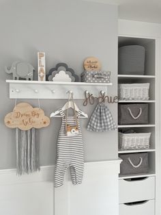 a baby's room with white shelves and gray accessories on the wall, hanging from hooks