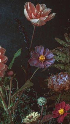 a bunch of flowers that are sitting on a table in front of a black background