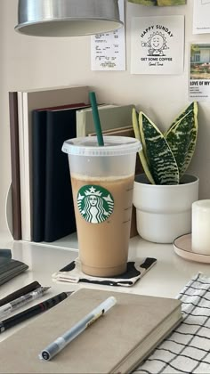 a cup of coffee sitting on top of a desk next to a pen and notebook