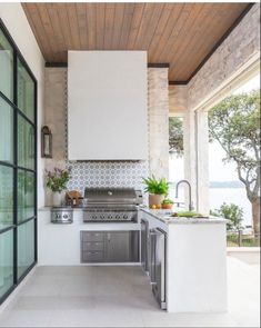 an outdoor kitchen with stainless steel appliances and white counter tops, along with glass doors