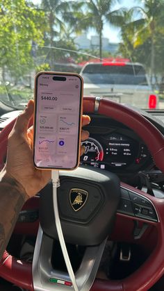 a person holding an iphone in their hand while sitting in the driver's seat of a car