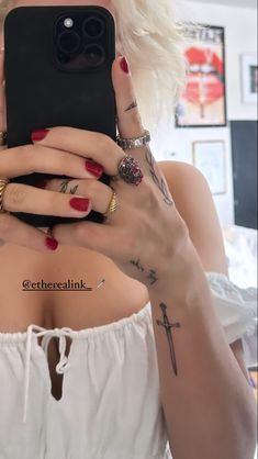 a woman taking a selfie with her cell phone in the mirror and tattoos on her arm