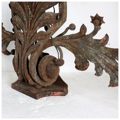 an ornate metal sculpture with leaves and scrolls on it's sides, against a white background