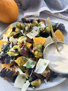 a white plate topped with brussel sprouts, oranges and cheese