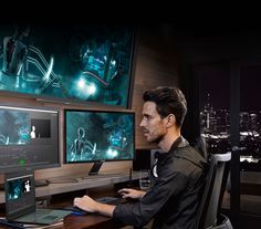 a man sitting at a desk in front of two computer monitors