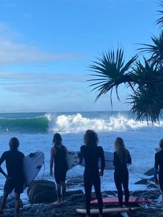 five people standing on the beach with surfboards