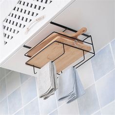 a wooden cutting board hanging from the side of a kitchen cabinet over a tiled wall