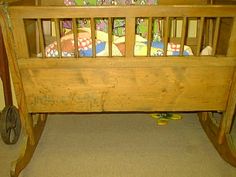 a wooden baby crib with wheels on the floor