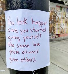 a handwritten note attached to a parking meter on a city street in front of storefronts