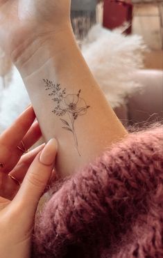 a woman's arm with a flower tattoo on the left side of her wrist