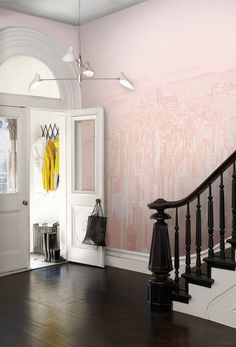 an entryway with a wooden floor and wallpaper on the walls, along with a black banister