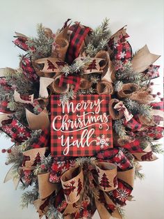 a christmas wreath that says merry christmas y'all with plaid ribbon and pine cones