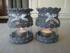 two crocheted glass jars with candles in them