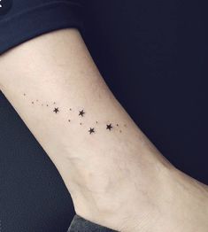 a small star tattoo on the ankle is shown in black and grey colors, with tiny stars all over it