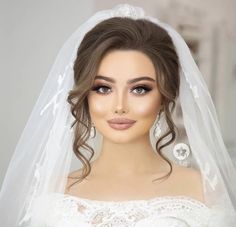 a woman wearing a wedding veil and makeup looks at the camera with an intense look on her face