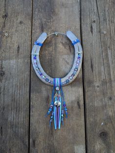 a necklace with beads and tassels hanging on a wooden floor next to a piece of wood