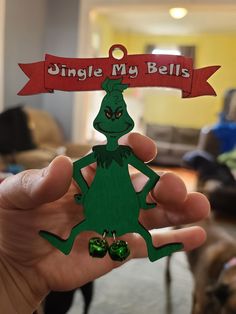 a person holding up a cut out of a green frog with a red sign that says, single my bells