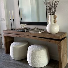 a table with two stools and a mirror on the wall behind it in a living room