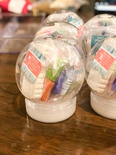 three clear plastic toothbrush holders sitting on top of a wooden table