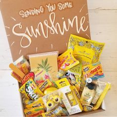 a box filled with snacks and candy sitting on top of a wooden table next to a sign