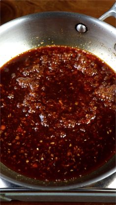 a pan filled with sauce on top of a wooden table