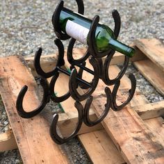 a wine bottle holder made out of wood pallets on the ground, with two bottles in it