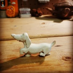 a small white dog figurine sitting on top of a wooden table next to other items