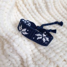 a blue and white knitted headband with snowflakes on it sitting on top of a blanket