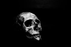 a black and white photo of a skull in the dark with only one eye open