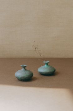 two green vases sitting next to each other on top of a brown countertop