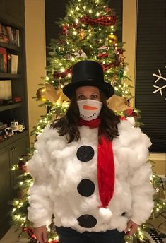 a woman standing in front of a christmas tree wearing a fake snowman face mask