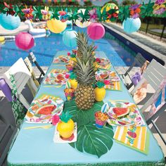 a pineapple sits on top of a table next to a pool with paper decorations