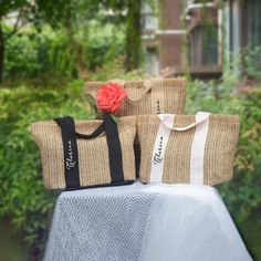 three bags sitting on top of a table with a rose in the middle and one bag next to it