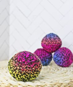 three crocheted balls sitting on top of a wicker basket next to each other