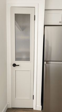 a white door in a kitchen next to a silver refrigerator and dishwasher on the floor