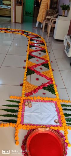 an arrangement of flowers on the floor in front of a man standing behind it,