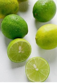 limes are cut in half and placed on a white surface with drops of water