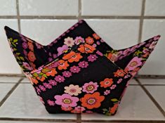 an origami flowered paper crown sitting on a tiled floor in front of a white tile wall