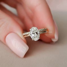 a woman's hand holding a ring with a diamond on the middle of it