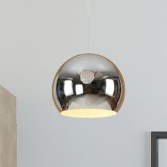 a round mirror hanging from the ceiling above a bed in a room with white walls