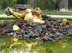 a golden statue sitting on top of a pile of rocks next to a body of water