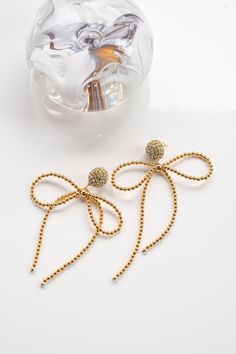 Interested in something a touch more unexpected? Lucia Earrings are a modern spin on a feminine classic—the bow. Tiny golden beads are strung tightly together and fashioned into a loose, flowing bow. In its center sits a statement bead, which hangs from a show-stopping rhinestone stud that bursts forth like a firework. You’ll have a hard time choosing from a handful of staple colors, but have no problem working Lucia Earrings into every occasion wear. She’s the perfect playful wink.24K Gold Plat Elegant Gold Beaded Jewelry For Parties, Elegant Gold Beads Jewelry For Evening, Elegant Gold Beaded Jewelry For Evening, Elegant Gold Beads Drop Earrings, Elegant Gold Beaded Drop Earrings, Elegant Gold Jewelry With Butterfly Knot, Chic Yellow Gold Jewelry With Bow Detail, Chic Yellow Gold Jewelry With Bow, Gold Dangle Jewelry With Bow