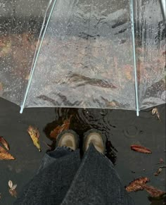 a person standing under an umbrella in the rain with their feet propped up on it