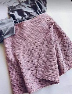 there is a pink crocheted skirt and jacket on the table next to it