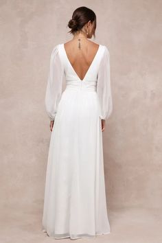 the back of a woman wearing a white dress with long sleeves and a low cut neckline