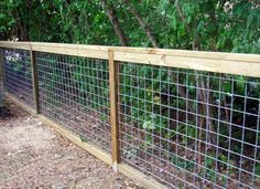 a fence that is made out of wood and metal wire with trees in the background