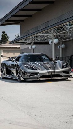 a silver and black sports car parked in front of a building with an awning