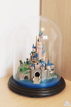 a snow globe with a castle in it on a wooden table next to a wall