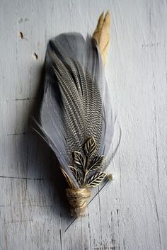 a feather with some sort of flower attached to it's side on a wooden surface